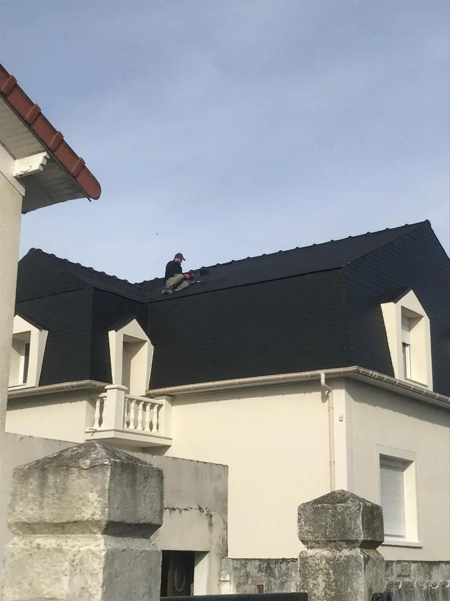 Couvreur sur le brisis d’un toit à la Mansart en ardoise