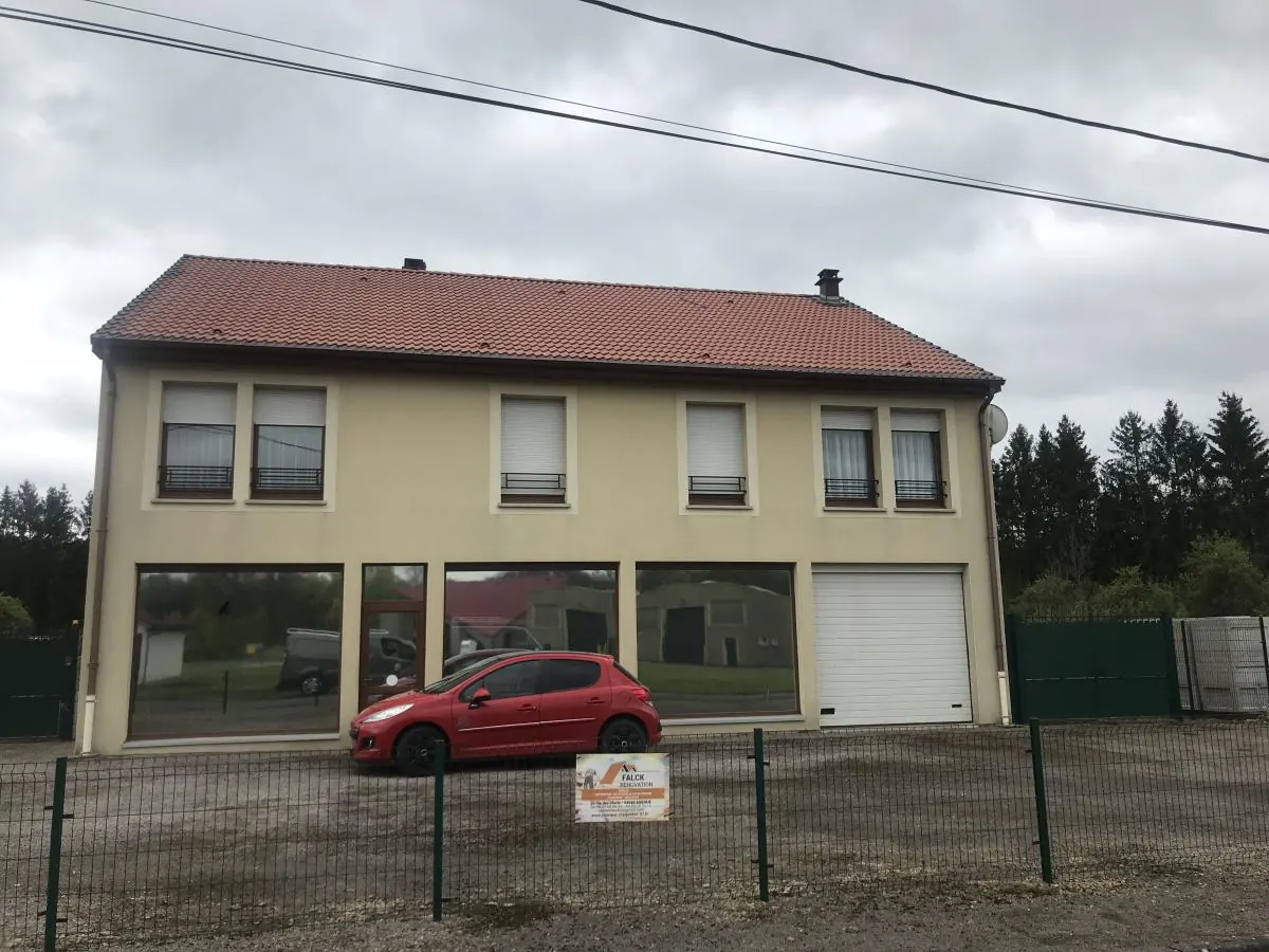 Grande maison à toiture en tuiles, panneau Falck Rénovation sur la clôture
